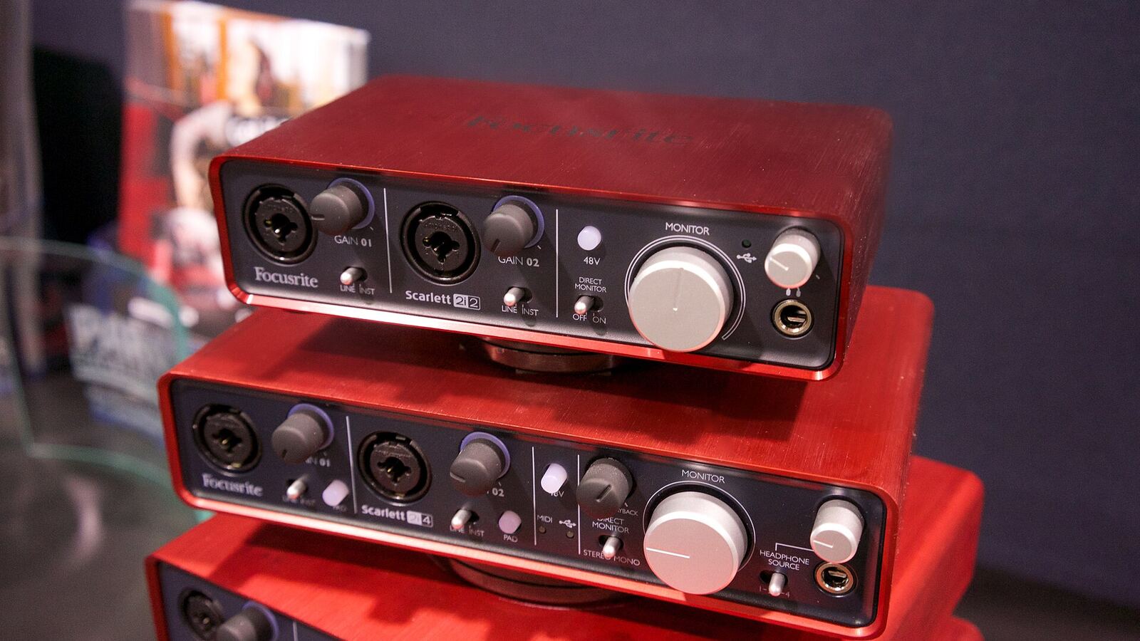 A stack of three small red USB audio interfaces, each with combo XLR inputs on the front, a large monitor knob and a headphone output.