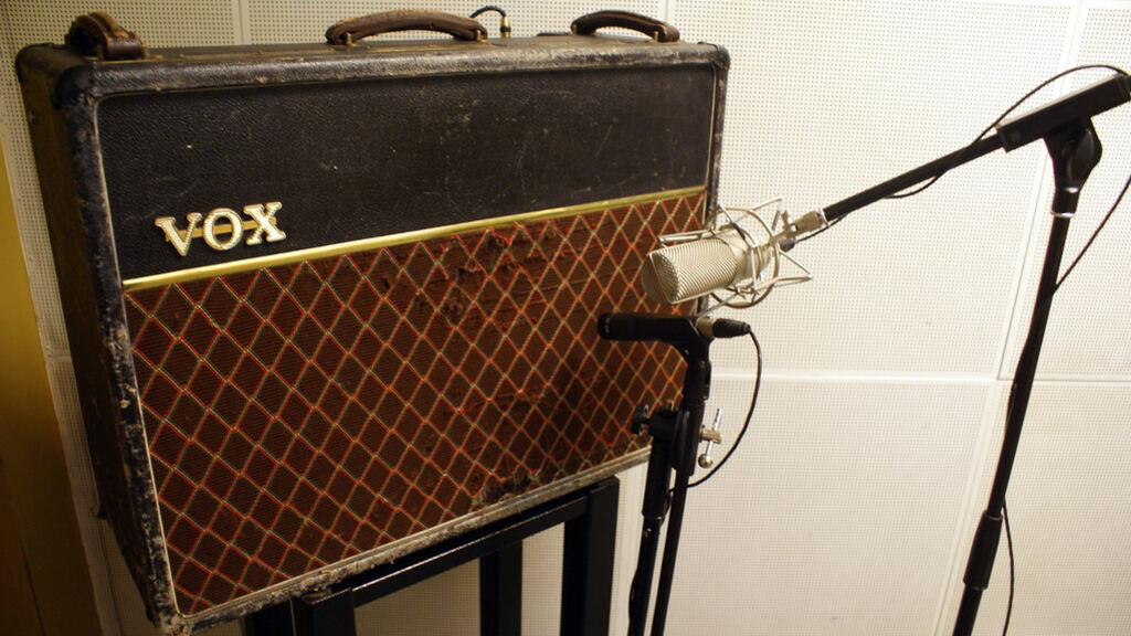 A vintage guitar combo amp with a microphone on a stand pointed close to the speaker grille.